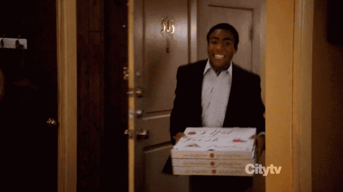 A gif of the scene in Community where Troy walks in with a bunch of pizza boxes all chipper and sees a scene of chaos and fire.