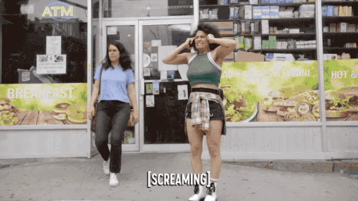 an animated GIF from the tv show 'Broad City' of a woman outside of a grocery store hunching over and screaming, with the caption "[screaming]"