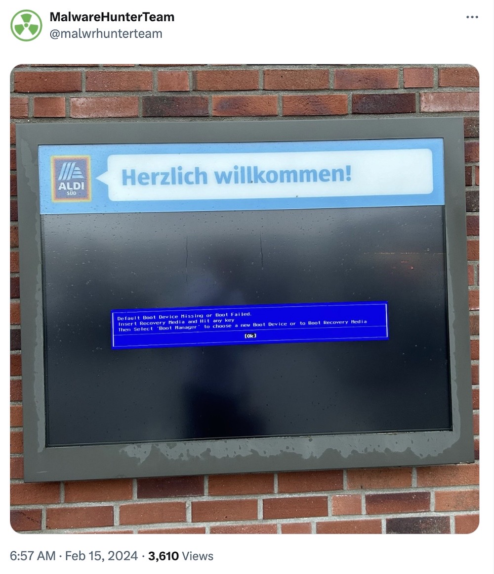 MalwareHunterTeam tweet, featuring a photo of an digital sign outside an Aldi supermarket in Germany, reads "Warm welcome," but has a boot error message saying the boot device can't be found.