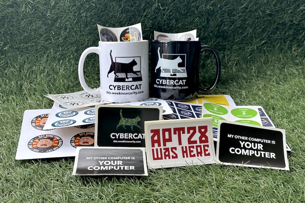 A selection of stickers made by Zack Whittaker, including two cybercat mugs (one in black, one in white), on a grassy background, 