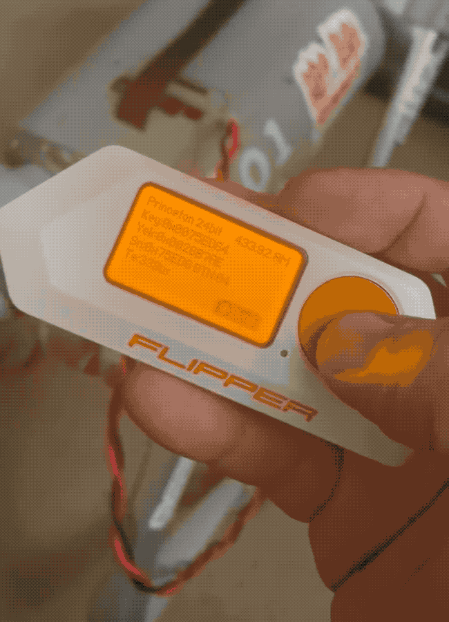 An animated GIF of a robot dog collapsing on the floor after a button is pressed on a Flipper Zero hacker multi-tool, which broadcasts a particular signal on a frequency that acts as the robot's kill switch. 