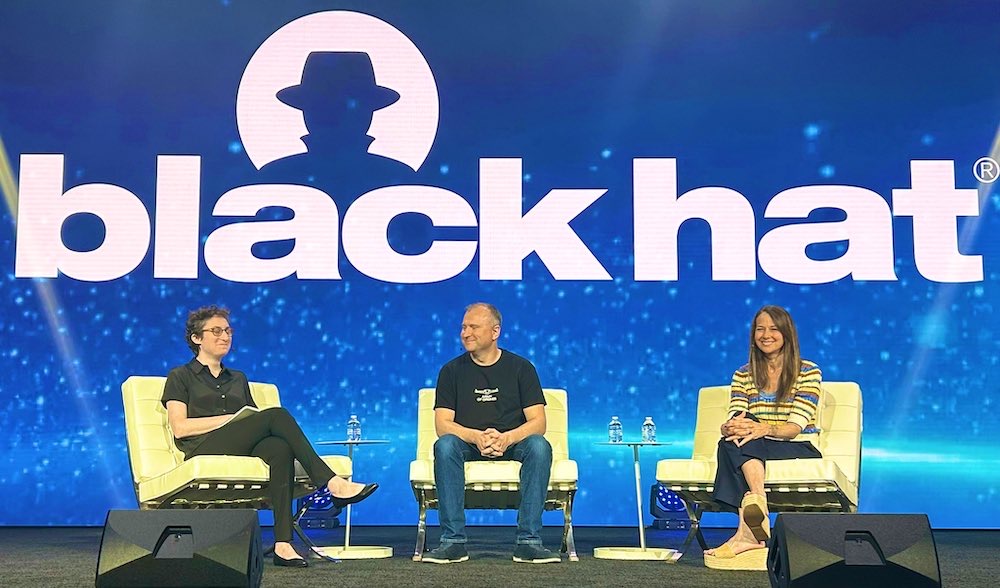 A photo of Lily Newman (left), Victor Zhora (center) and Jen Easterly (right) sat on stage at the Black Hat conference.