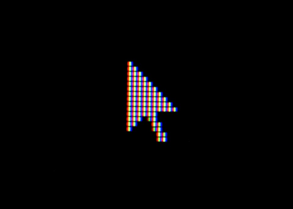 a close up photo of a cursor on a display and black background, shown as very pixelated. 